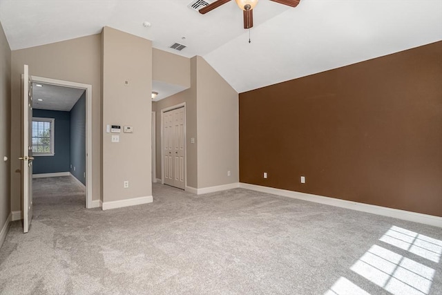 interior space featuring baseboards, vaulted ceiling, visible vents, ceiling fan, and light colored carpet