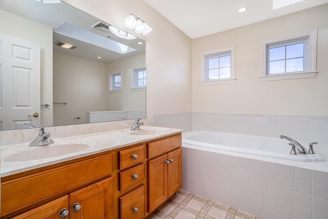bathroom with a garden tub, visible vents, a sink, and a skylight