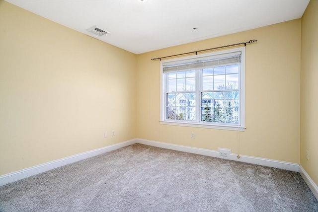 empty room featuring carpet, visible vents, and baseboards