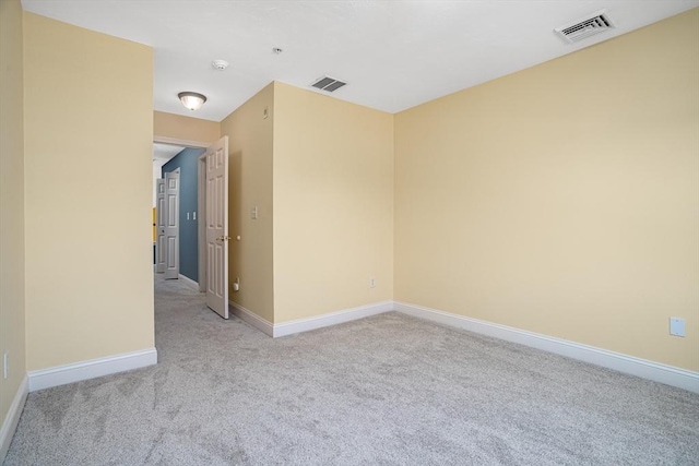 empty room with light carpet, visible vents, and baseboards