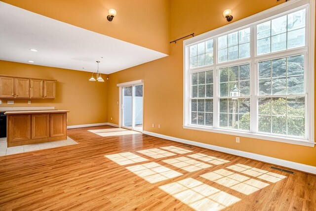 unfurnished living room featuring visible vents, light wood-style flooring, and a healthy amount of sunlight