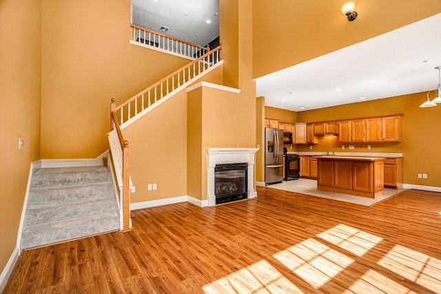 unfurnished living room featuring light wood-type flooring, a sink, baseboards, and stairs