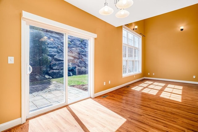 interior space with visible vents, baseboards, a chandelier, and wood finished floors