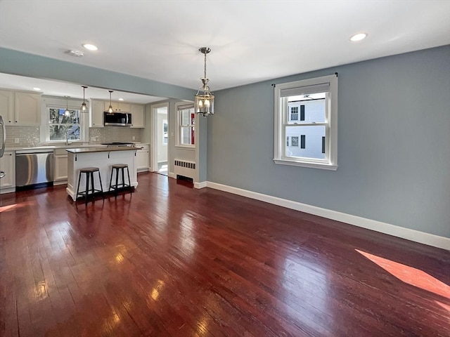 unfurnished living room with radiator, dark wood-style floors, baseboards, and recessed lighting