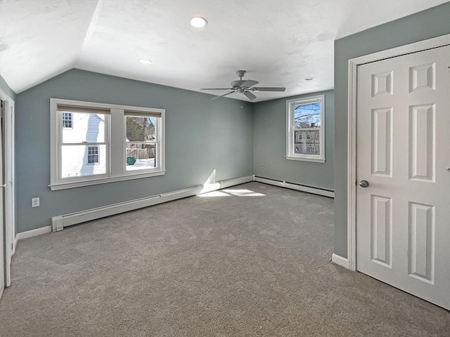 unfurnished bedroom featuring carpet floors, multiple windows, a baseboard heating unit, and lofted ceiling