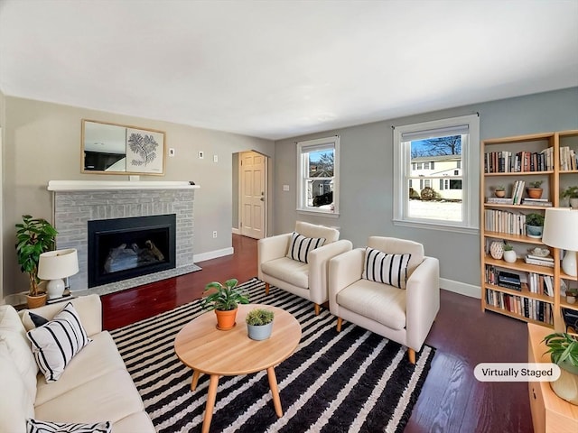 living room with a brick fireplace, baseboards, and wood finished floors