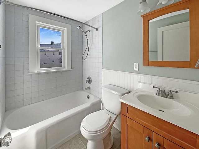 bathroom with toilet, vanity, wainscoting, tub / shower combination, and tile patterned floors