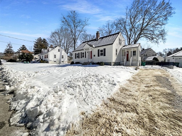 snow covered property featuring a chimney and fence