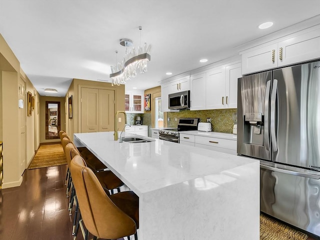 188 Atlantic St, Gloucester, MA 01930 - kitchen with stainless steel appliances, a kitchen island with sink, decorative backsplash, dark wood-style flooring, and white cabinets