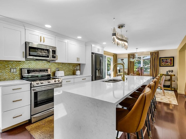 188 Atlantic St, Gloucester, MA 01930 - kitchen featuring appliances with stainless steel finishes, an island with sink, white cabinetry, tasteful backsplash, and light countertops