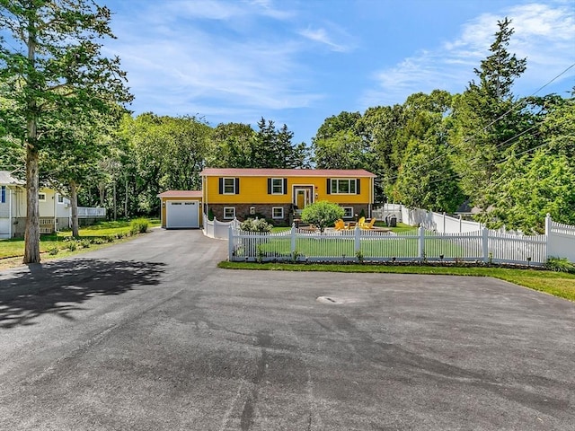 188 Atlantic St, Gloucester, MA 01930 - bi-level home featuring asphalt driveway, a garage, a fenced front yard, and view of scattered trees