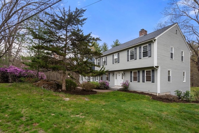 colonial inspired home featuring a chimney and a front yard