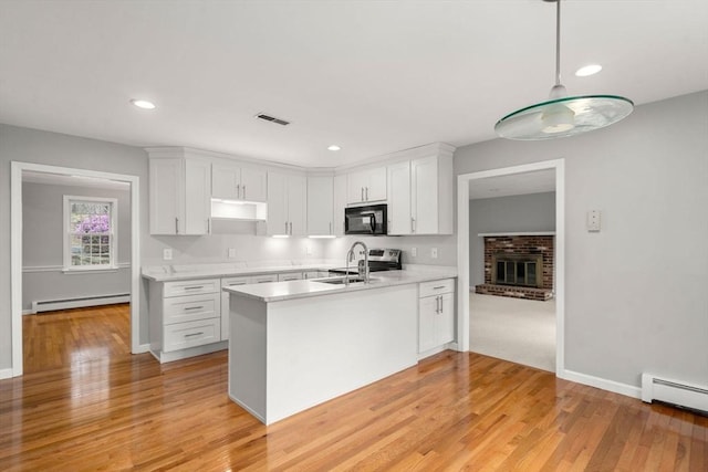 kitchen featuring visible vents, black microwave, light wood-style floors, light countertops, and a baseboard radiator