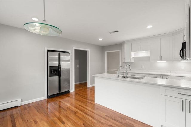 kitchen featuring a sink, visible vents, stainless steel fridge with ice dispenser, light countertops, and a baseboard heating unit