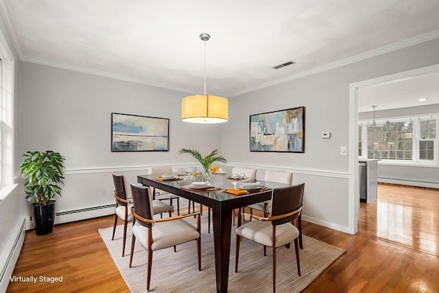 dining room with visible vents, wood finished floors, and a baseboard radiator