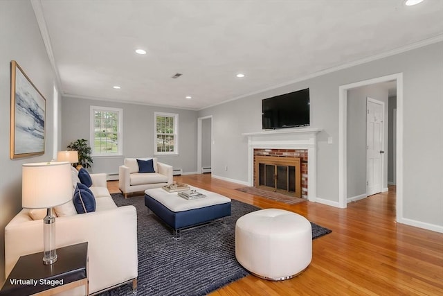 living area featuring visible vents, ornamental molding, wood finished floors, a fireplace, and a baseboard heating unit