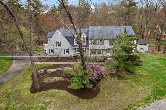 shingle-style home with a chimney and a front yard