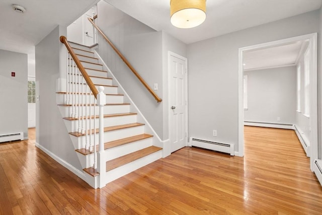 stairs with baseboards, baseboard heating, and wood-type flooring