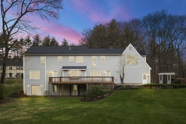 rear view of property with a chimney, a yard, and a deck