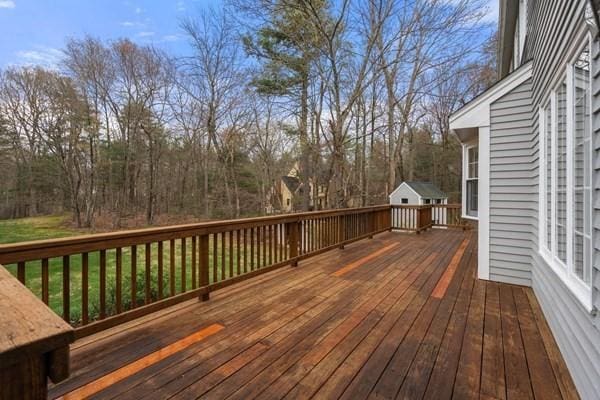 wooden terrace featuring an outdoor structure and a storage unit