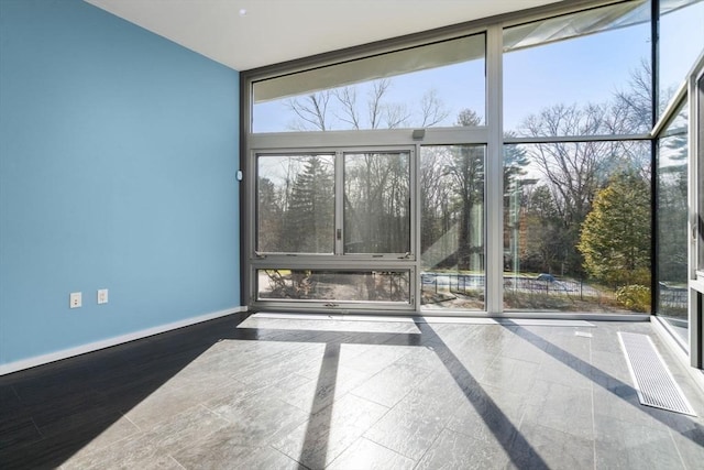 empty room with expansive windows and baseboards