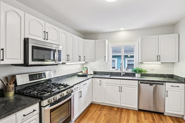 20 Lake St Unit 2, Somerville, MA 02143 - kitchen with stainless steel appliances, a sink, white cabinets, light wood-type flooring, and recessed lighting