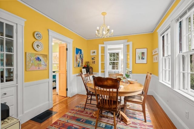 21 Marsh St, Dedham, MA 02026 - dining area with wainscoting, a chandelier, and light wood-style floors
