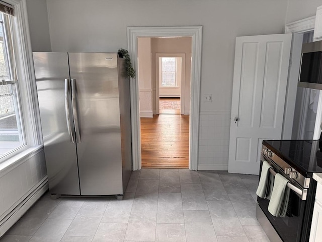 kitchen with white cabinetry, a baseboard radiator, stainless steel appliances, and light tile patterned floors