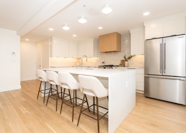 kitchen with backsplash, light hardwood / wood-style flooring, white cabinetry, and high end fridge