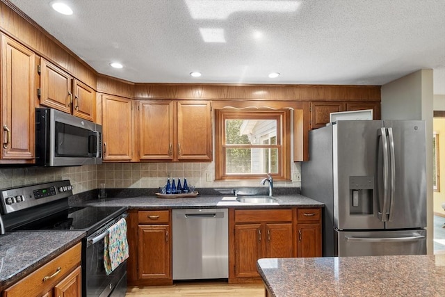 65 Martin Rd, Tewksbury, MA 01876 - kitchen featuring appliances with stainless steel finishes, brown cabinets, tasteful backsplash, a textured ceiling, and light wood-style flooring