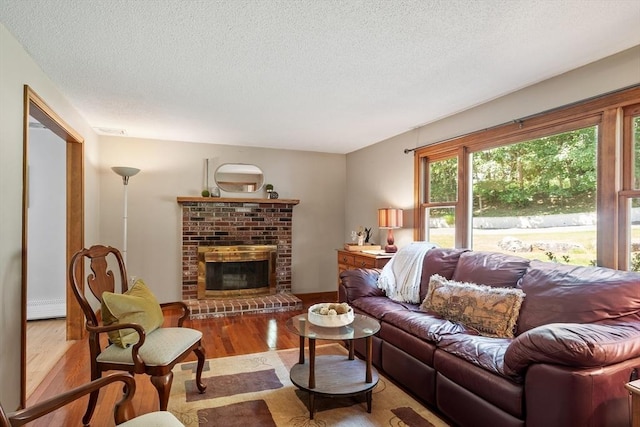 65 Martin Rd, Tewksbury, MA 01876 - living area featuring a textured ceiling, wood finished floors, baseboard heating, and a brick fireplace