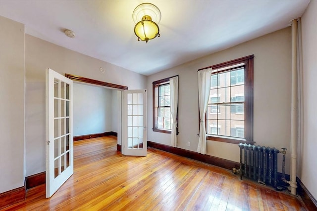 70 Revere St Unit 5, Boston, MA 02114 - empty room with french doors, light wood-style floors, radiator, baseboards, and a smoke detector