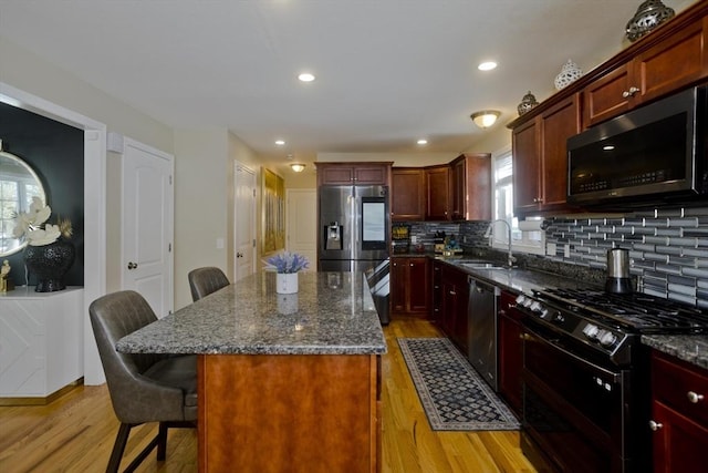 kitchen with stainless steel appliances, light wood-style floors, a sink, and a kitchen breakfast bar