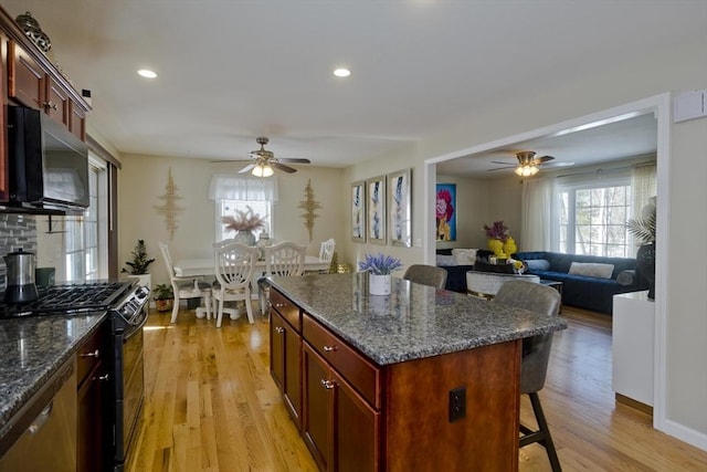 kitchen featuring light wood-style floors, a breakfast bar, a kitchen island, and black appliances