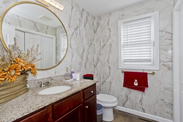 bathroom with baseboards, visible vents, vanity, and toilet