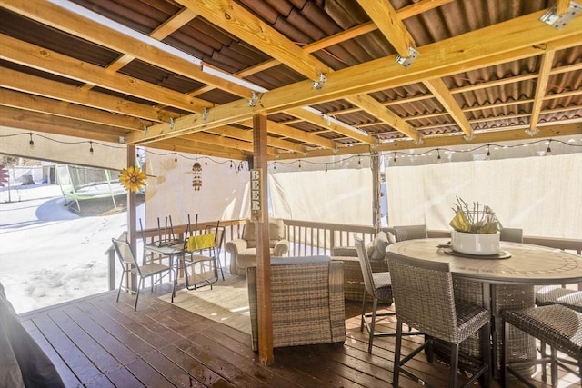 wooden deck with outdoor dining space, a trampoline, and outdoor lounge area