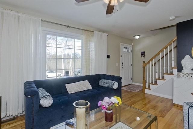 living area featuring baseboards, stairway, and wood finished floors