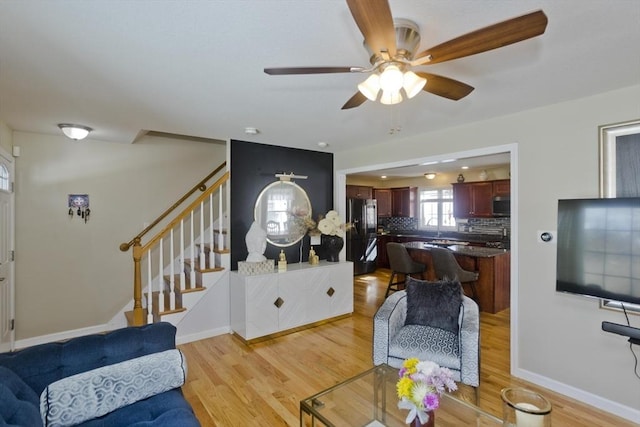 living room featuring light wood-style flooring, stairs, and baseboards