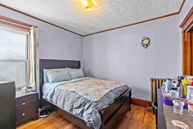 bedroom with baseboards, wood-type flooring, and crown molding