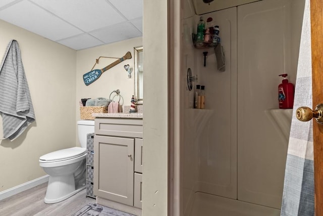 full bathroom with baseboards, toilet, wood finished floors, vanity, and a paneled ceiling