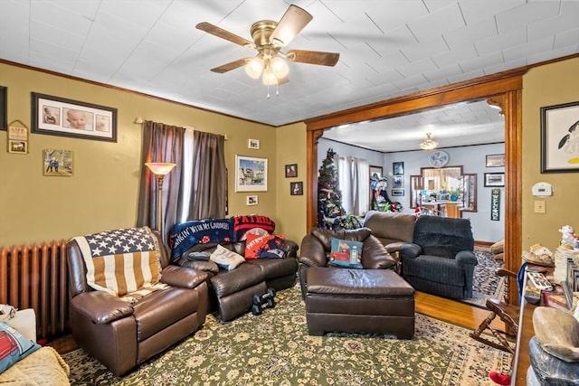 living area featuring radiator, a ceiling fan, ornamental molding, and wood finished floors