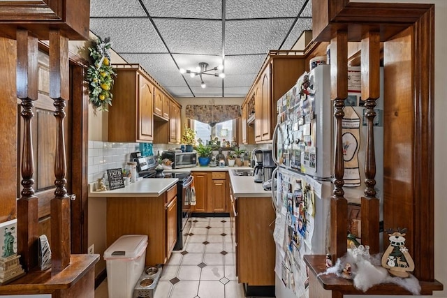 kitchen featuring a drop ceiling, stainless steel appliances, a sink, light countertops, and backsplash