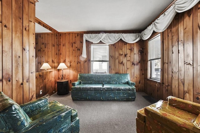 living area with plenty of natural light, carpet flooring, and wooden walls