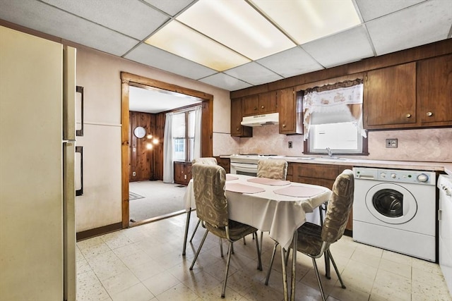 kitchen featuring washer / dryer, light flooring, a paneled ceiling, under cabinet range hood, and light countertops