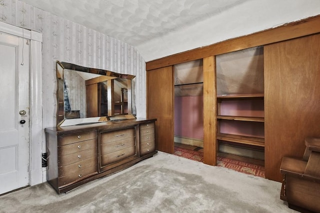unfurnished bedroom featuring wallpapered walls and lofted ceiling