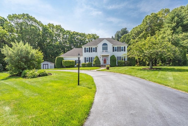 113 Sparrow Rd, Stoughton, MA 02072 - colonial-style house with a storage shed, curved driveway, a front lawn, and stucco siding