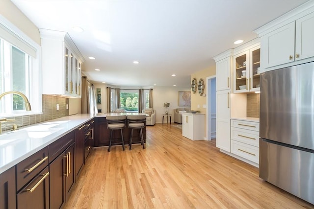 113 Sparrow Rd, Stoughton, MA 02072 - kitchen featuring stainless steel fridge, light wood-style flooring, recessed lighting, decorative backsplash, and light countertops