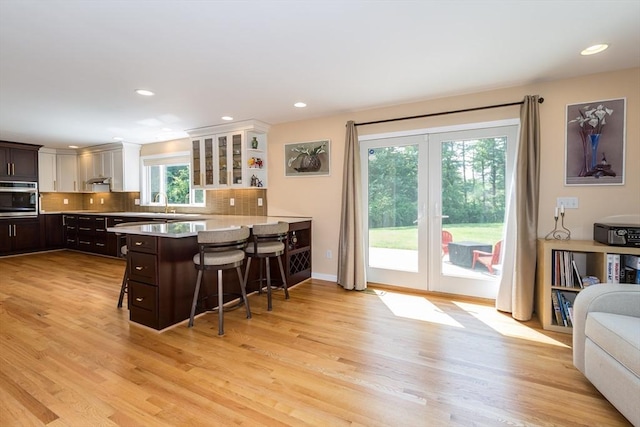 113 Sparrow Rd, Stoughton, MA 02072 - kitchen featuring oven, a breakfast bar area, dark brown cabinets, light countertops, and light wood-style flooring