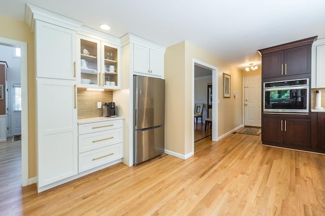 113 Sparrow Rd, Stoughton, MA 02072 - kitchen with stainless steel appliances, light wood-style flooring, glass insert cabinets, tasteful backsplash, and light countertops