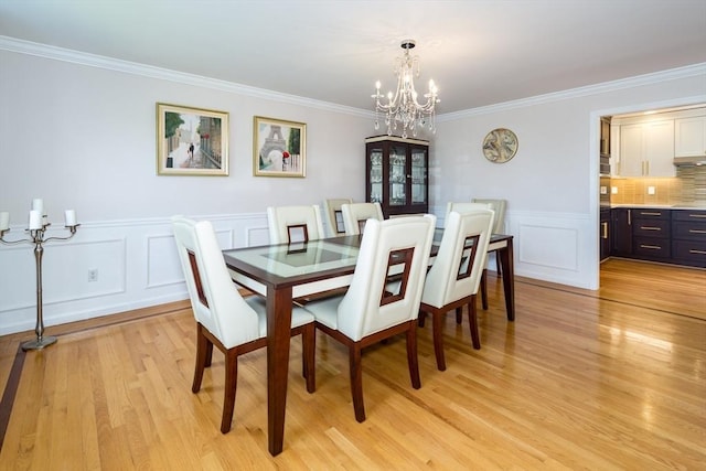 113 Sparrow Rd, Stoughton, MA 02072 - dining room with a chandelier, a decorative wall, ornamental molding, light wood finished floors, and wainscoting